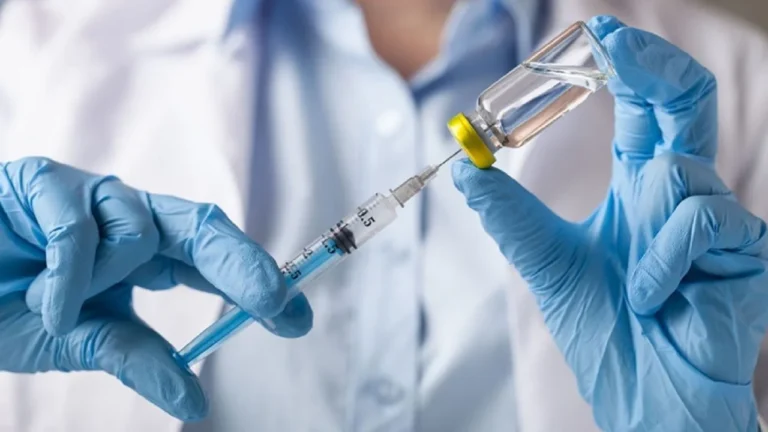 Médico mostrando una jeringa y un calendario de vacunación